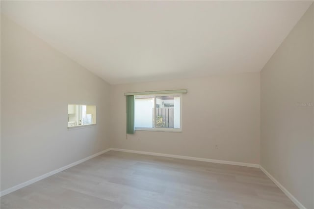 empty room with light hardwood / wood-style floors and vaulted ceiling