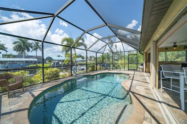 view of swimming pool with glass enclosure, ceiling fan, and a patio