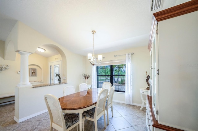 tiled dining space featuring an inviting chandelier and decorative columns