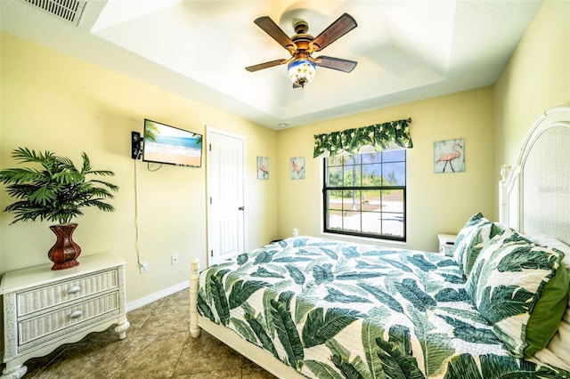 tiled bedroom with a raised ceiling and ceiling fan