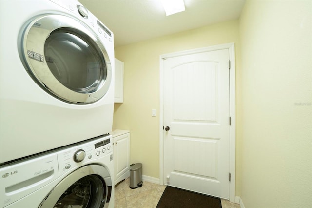 laundry area with cabinets, light tile patterned floors, and stacked washer / dryer