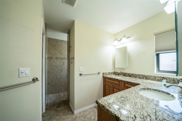 bathroom with tile patterned floors, vanity, and a tile shower