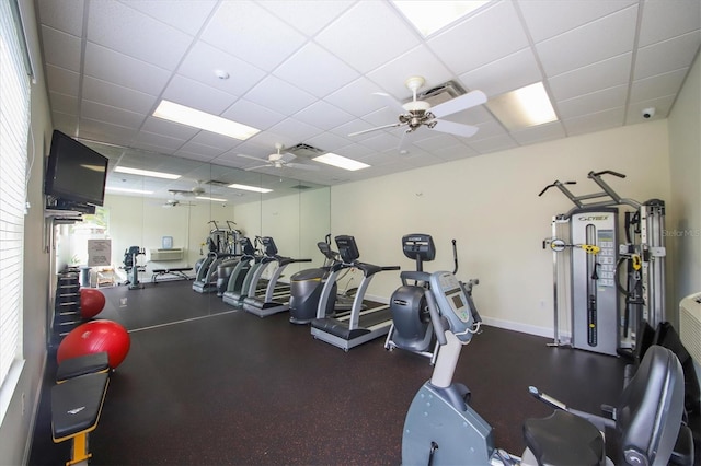 workout area with ceiling fan, a healthy amount of sunlight, and a drop ceiling