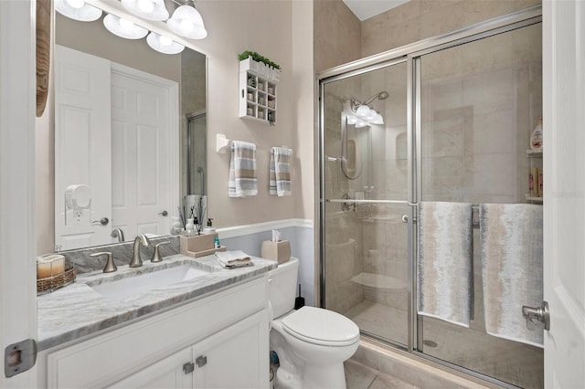 bathroom featuring vanity, toilet, tile patterned floors, and an enclosed shower