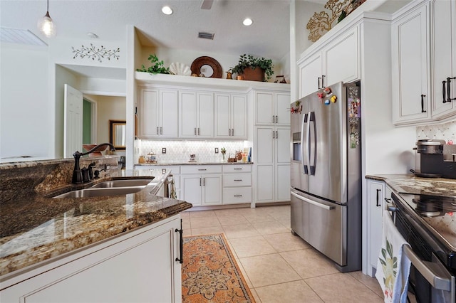 kitchen with dark stone counters, sink, white cabinets, decorative light fixtures, and appliances with stainless steel finishes