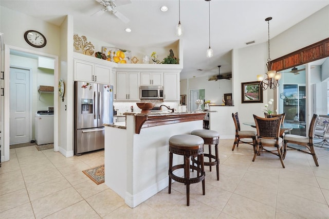 kitchen with white cabinets, decorative light fixtures, stainless steel appliances, and ceiling fan with notable chandelier