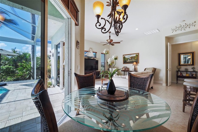 tiled dining space featuring a healthy amount of sunlight and ceiling fan with notable chandelier