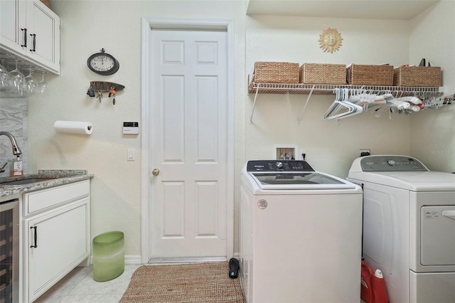 washroom featuring sink, washing machine and dryer, cabinets, and light tile patterned floors