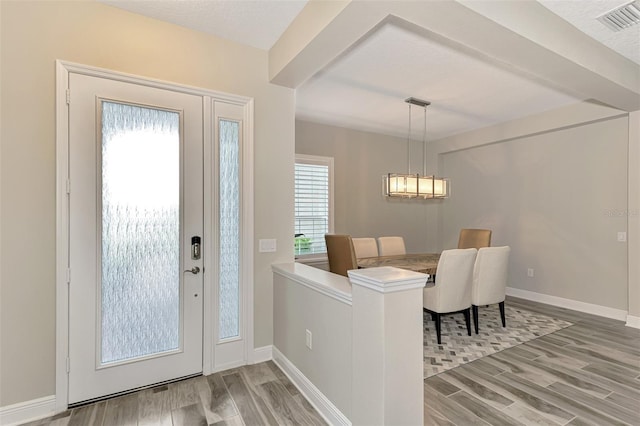 foyer featuring a textured ceiling, hardwood / wood-style flooring, and an inviting chandelier