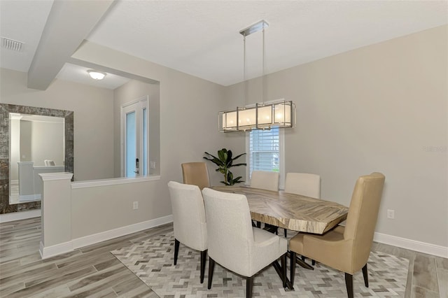 dining room featuring beam ceiling and light wood-type flooring