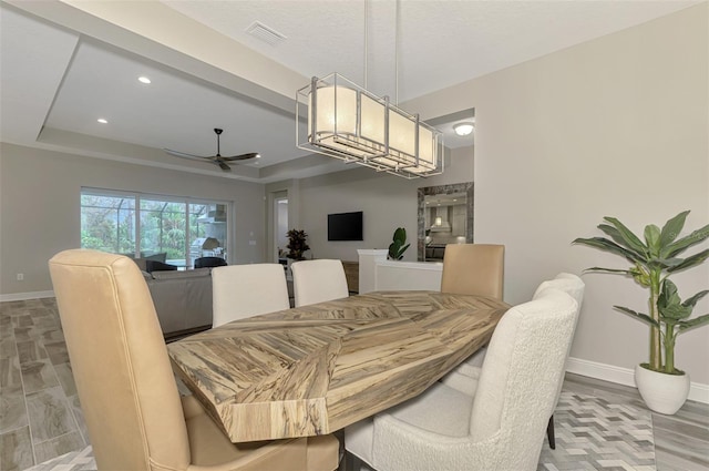 dining area featuring hardwood / wood-style floors, ceiling fan, and a tray ceiling