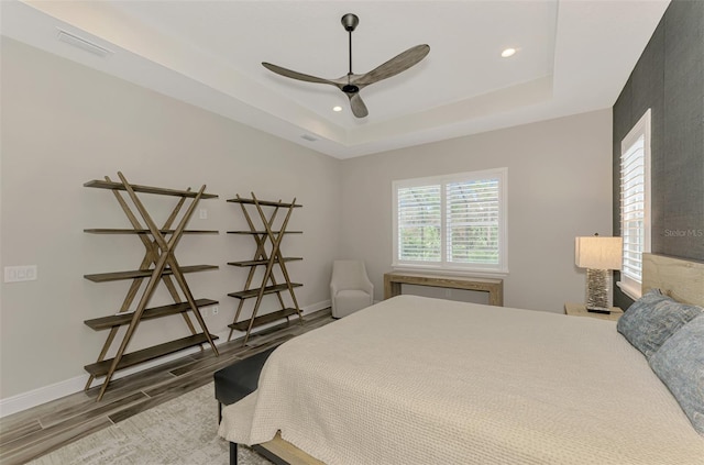 bedroom featuring hardwood / wood-style flooring, ceiling fan, and a tray ceiling