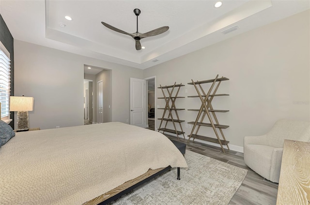 bedroom featuring wood-type flooring, ceiling fan, and a raised ceiling