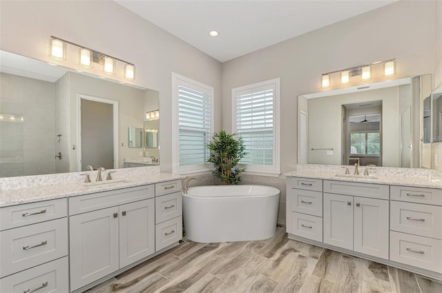 full bath with a sink, a tile shower, and two vanities