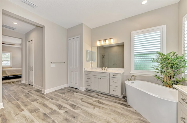 ensuite bathroom featuring vanity, visible vents, recessed lighting, a soaking tub, and a stall shower