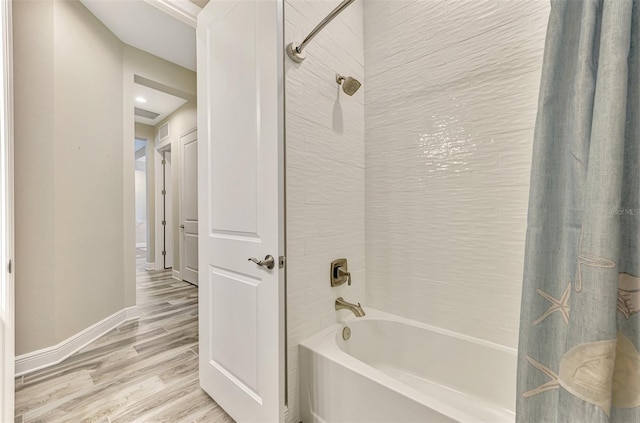bathroom with baseboards, shower / bath combo, wood finished floors, and visible vents