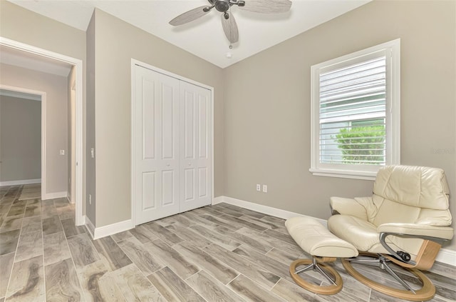 living area with baseboards, a ceiling fan, and light wood finished floors