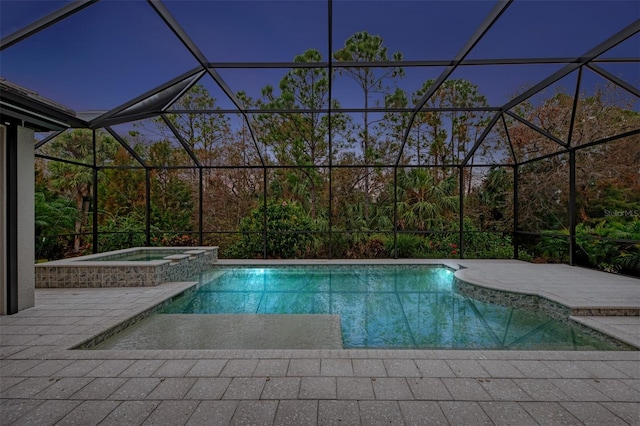 pool at dusk with a patio, a lanai, and an in ground hot tub