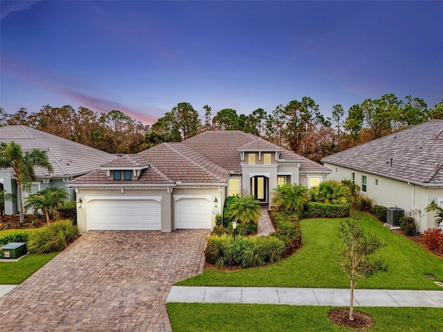 mediterranean / spanish home with a garage, central AC unit, and a lawn