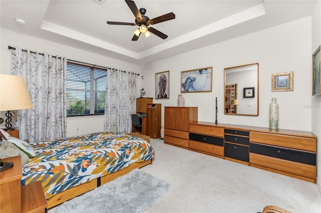 bedroom featuring carpet floors, ceiling fan, and a tray ceiling