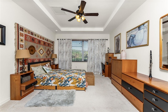 bedroom with ceiling fan, light carpet, and a raised ceiling