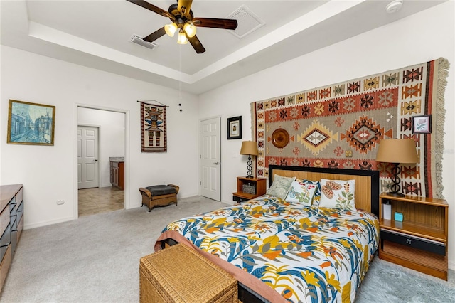 carpeted bedroom featuring ceiling fan and a tray ceiling