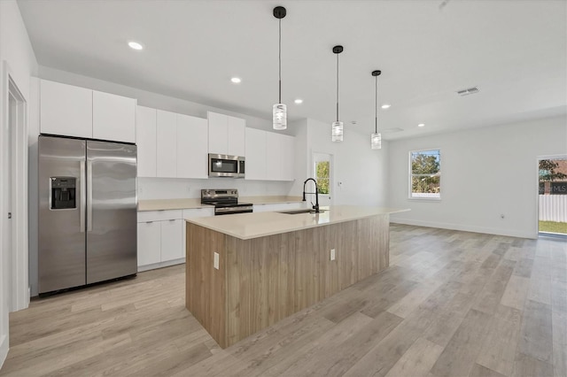 kitchen featuring white cabinetry, a kitchen island with sink, light hardwood / wood-style flooring, sink, and stainless steel appliances