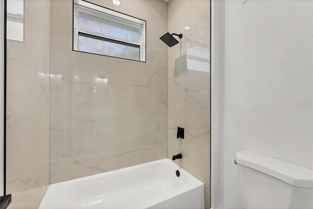 bathroom featuring tiled shower / bath combo and toilet