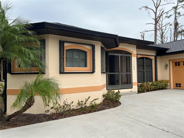 doorway to property with concrete driveway, a garage, and stucco siding