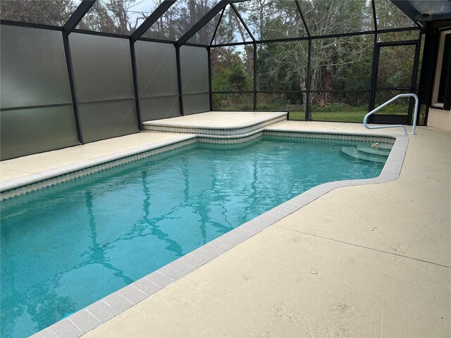 pool with a patio and glass enclosure