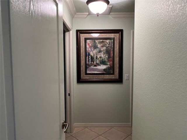 hallway with crown molding, baseboards, and tile patterned floors
