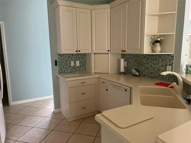 kitchen featuring dishwasher, sink, light tile patterned flooring, and white cabinets