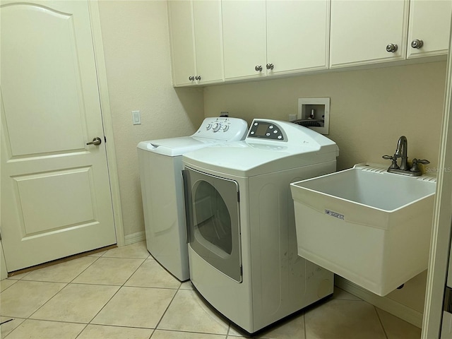 clothes washing area featuring cabinets, sink, light tile patterned floors, and independent washer and dryer