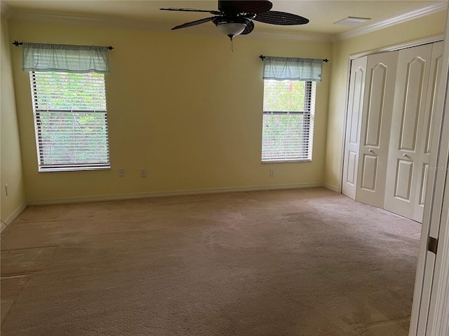 unfurnished bedroom with ceiling fan, a closet, ornamental molding, and light carpet