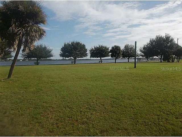 surrounding community with a water view and a lawn