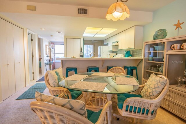 dining space featuring light carpet