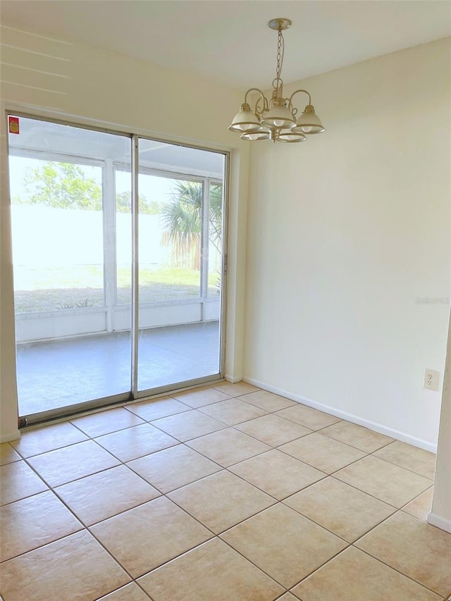 tiled empty room featuring a notable chandelier