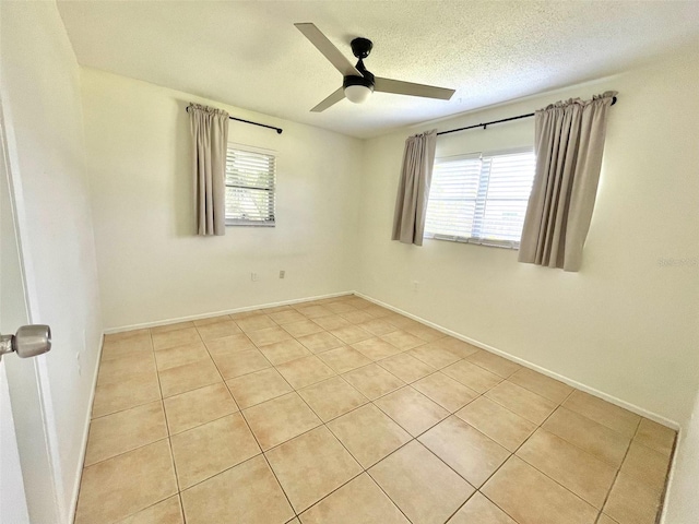 empty room featuring ceiling fan, light tile patterned flooring, and a wealth of natural light