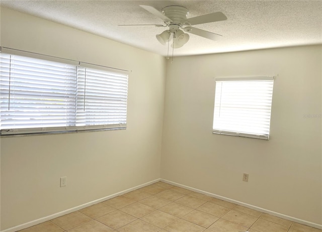 spare room with a textured ceiling, light tile patterned flooring, and ceiling fan