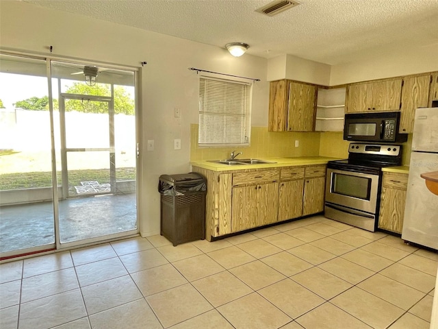 kitchen with backsplash, light tile patterned floors, stainless steel electric range oven, sink, and white refrigerator