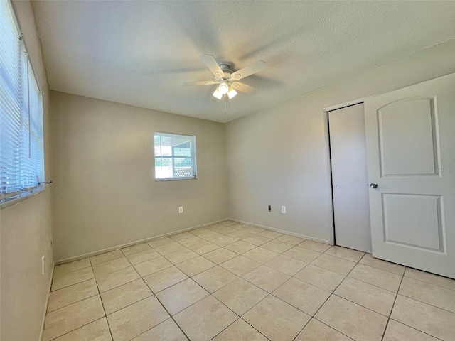 unfurnished bedroom featuring a textured ceiling, light tile patterned floors, and ceiling fan