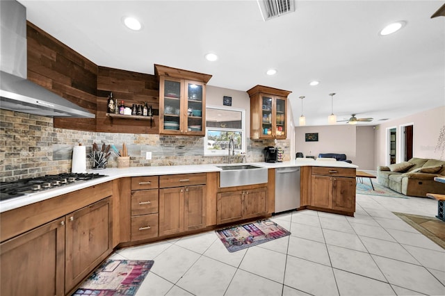 kitchen with wall chimney range hood, stainless steel appliances, sink, pendant lighting, and tasteful backsplash