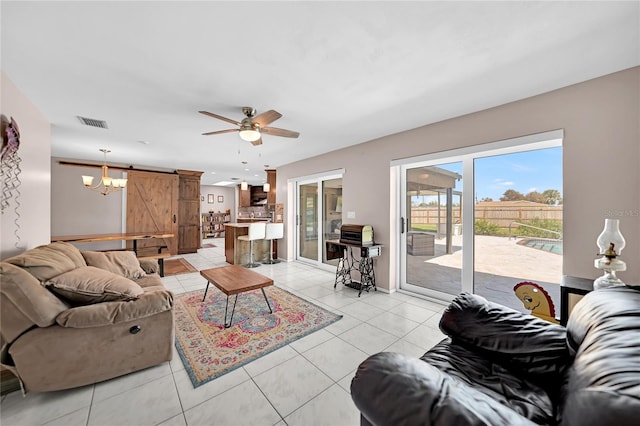 living room featuring ceiling fan, light tile patterned floors, and a barn door