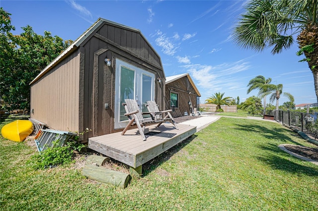 rear view of property with a deck, a shed, and a lawn