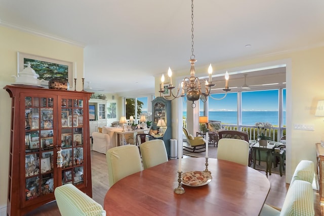 dining area featuring wood-type flooring, a water view, a chandelier, and crown molding