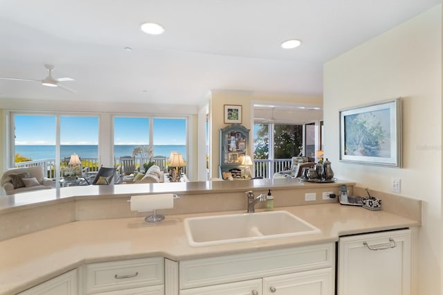 kitchen featuring a water view, dishwasher, ceiling fan, sink, and white cabinetry