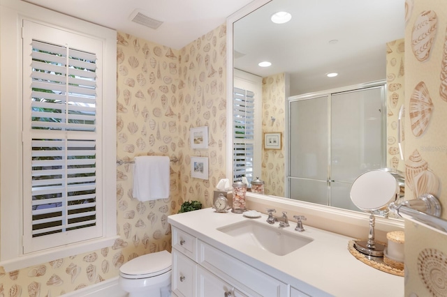 bathroom with toilet, vanity, and an enclosed shower