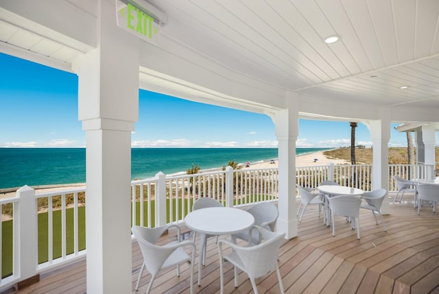 wooden terrace with a water view and a view of the beach