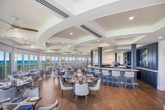 dining room featuring coffered ceiling, dark wood-type flooring, a water view, and ceiling fan