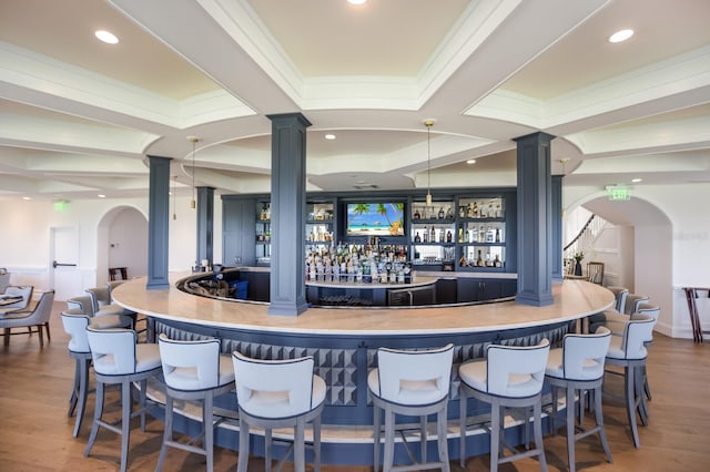 bar featuring crown molding, ornate columns, and dark wood-type flooring